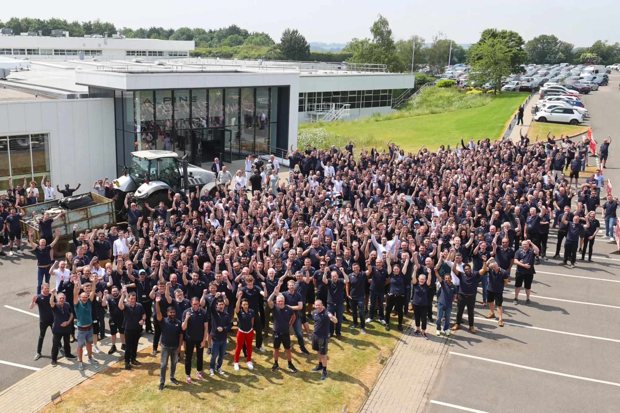 Alpine F1 team taking a group photo as Jeremy Clarkson delivers his beer to the team factory